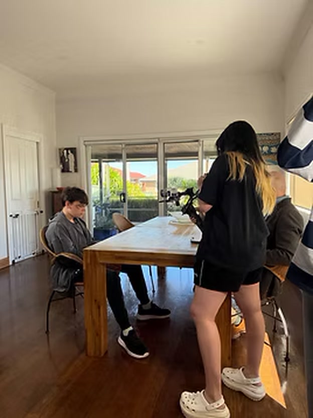 Camera operator filming actors around a dining table